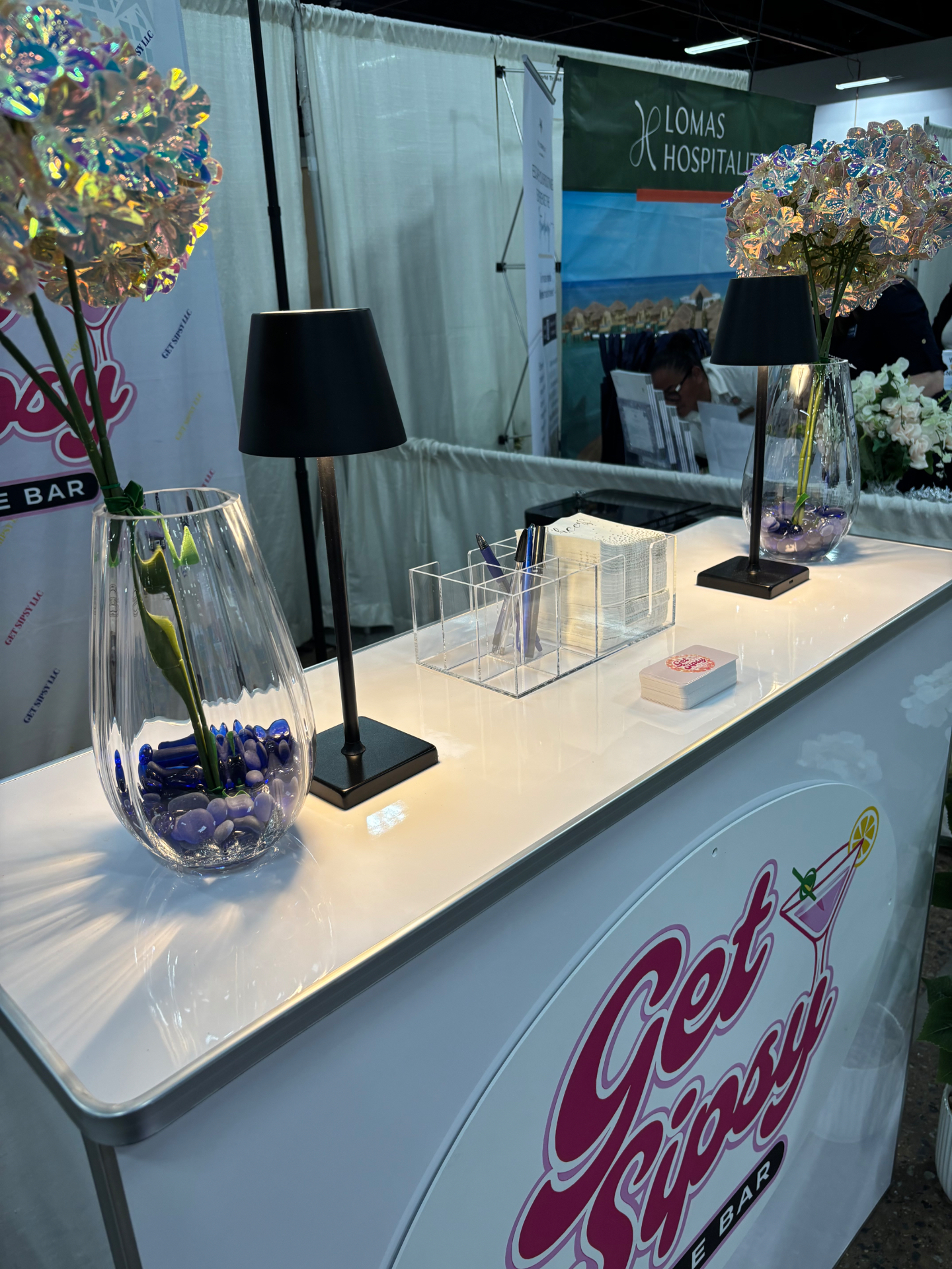 Get Sipsy bar counter styled with iridescent florals and modern lamps at an event
